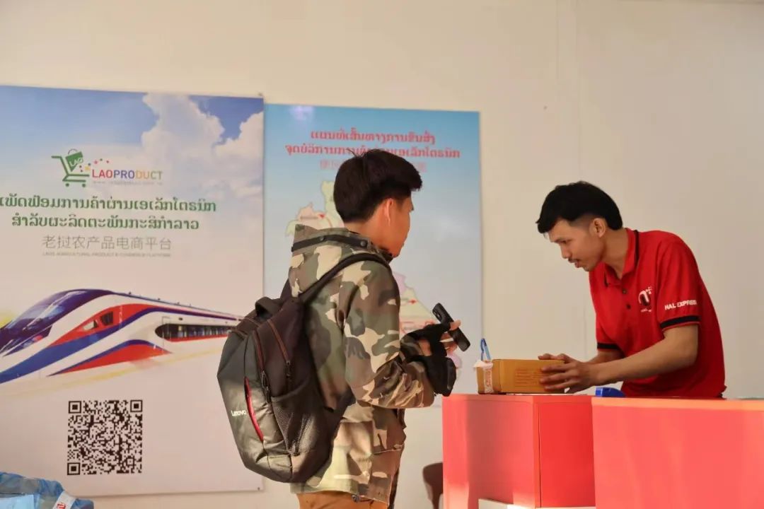 在位于老挝万象的一处快递收发站,工作人员正在与前来取件的客户核对收货信息。杨 一摄