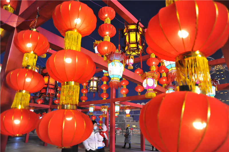 哈尔滨市道里区松花江畔,游人们有的在观赏红灯笼,用手机拍下美丽瞬间