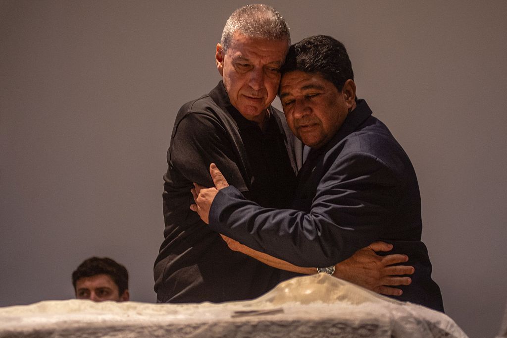 当地时间2024年1月7日，巴西里约热内卢，巴西足协主席埃德纳尔多·罗德里格斯(右)与巴西足球传奇人物马里奥·扎加洛的儿子马里奥·塞萨尔·扎加洛拥抱，悼念逝者宽慰其家人。（图源 视觉中国）