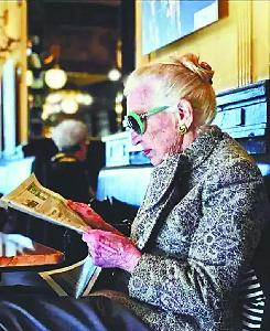 一位打扮精致的老太太在读报。