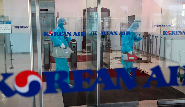 2月25日,韩国航空仁川运营中心,佩戴防护装备的工人正在喷洒消毒剂,以预防新型冠状病毒传播。(来源:韩联社、美联社)