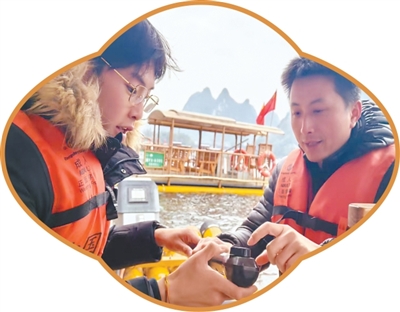 广西漓江景区，筏工（右）在向游客介绍电动排筏。本报记者 张云河摄