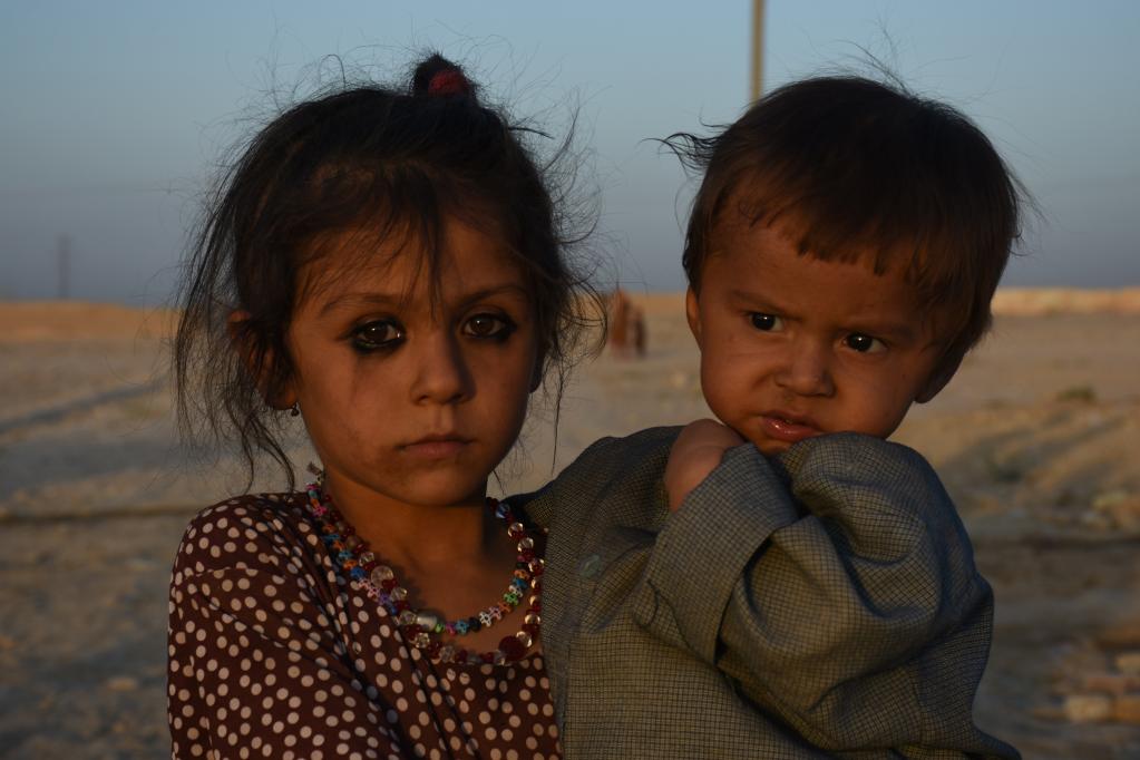 9月16日，一名女孩抱着弟弟待在阿富汗马扎里沙里夫一处无家可归者的营地里。新华社发（卡瓦·巴沙拉特摄）