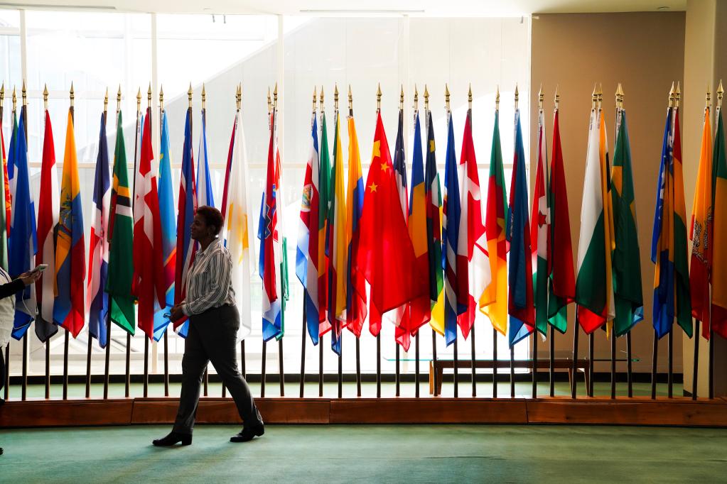 2021年10月20日,一名女子从纽约联合国总部联大会堂外的国旗展示区