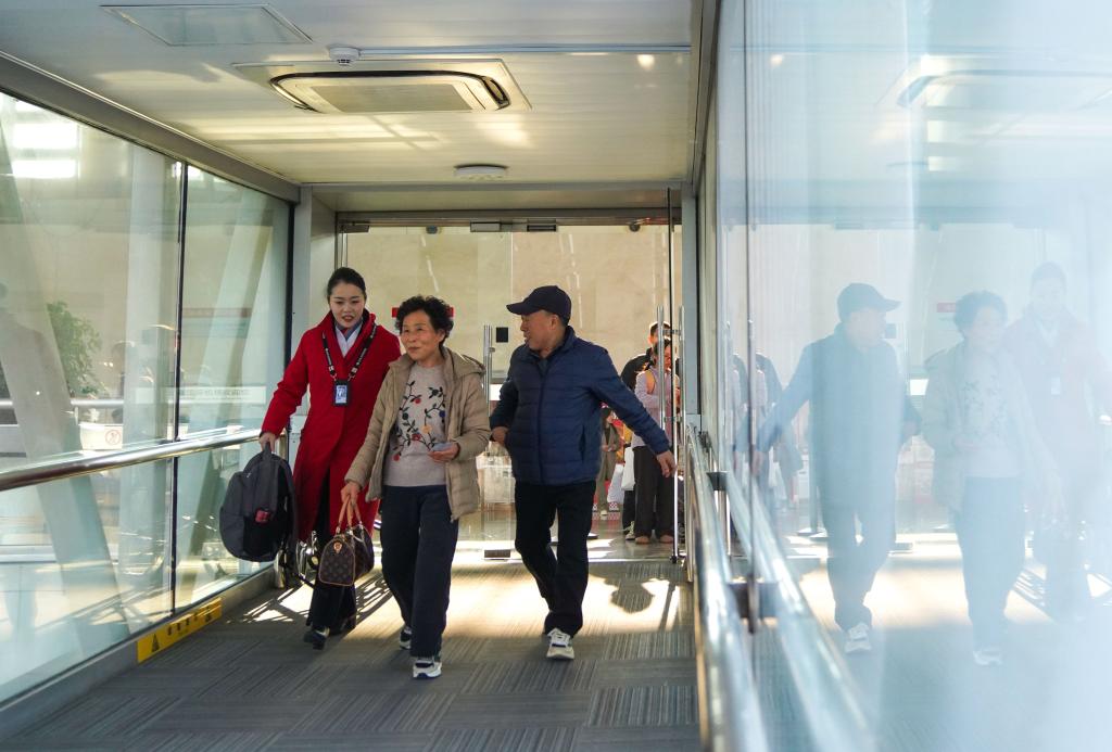 2月13日，在长春龙嘉国际机场，中国南方航空公司工作人员（左）引导“银发”旅客登机。新华社记者 许畅 摄